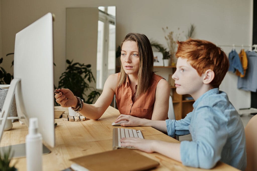 mother explaining her son how to use computer