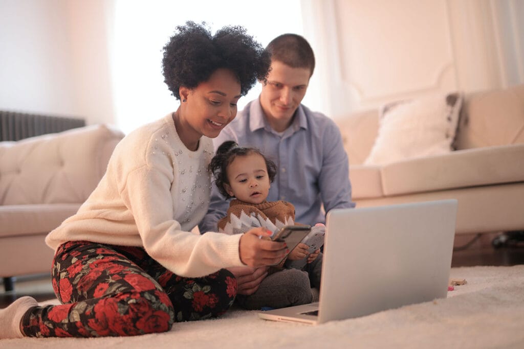 parents with baby using smartphone and computer