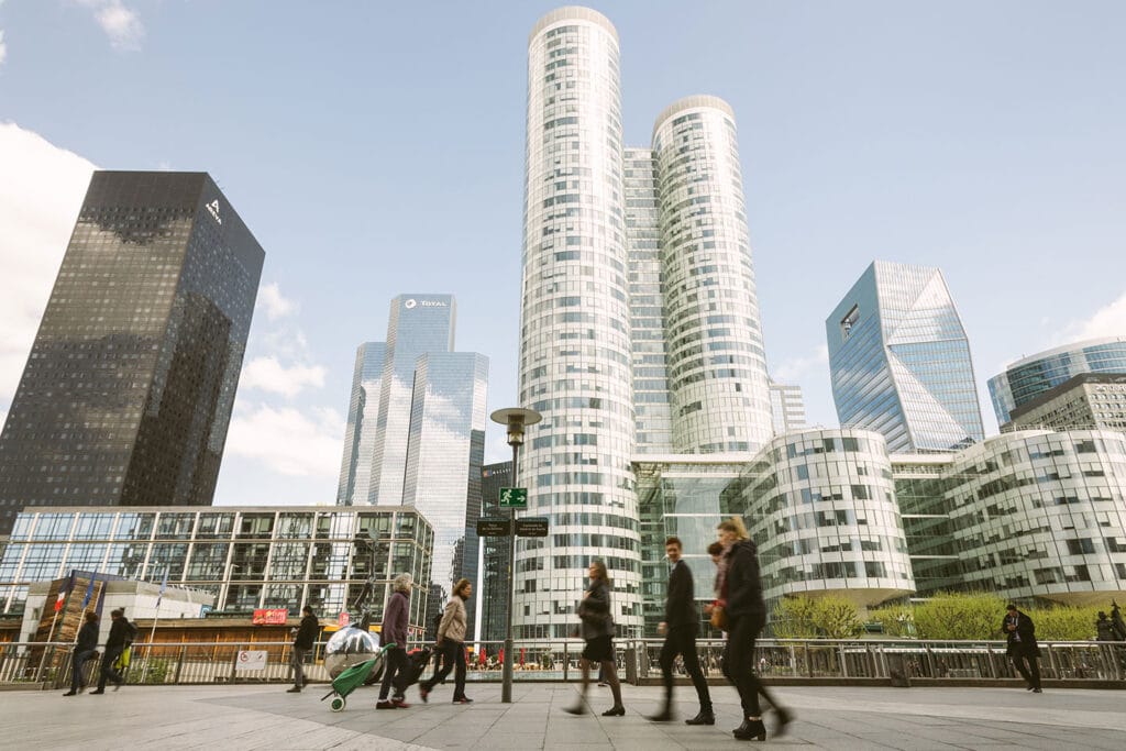 people walking near a green park in a modern city