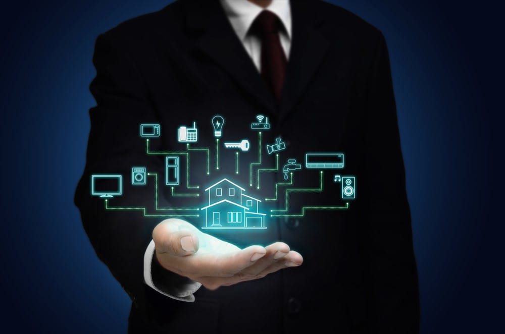 Man's hand holding graphic of home with connected smart devices