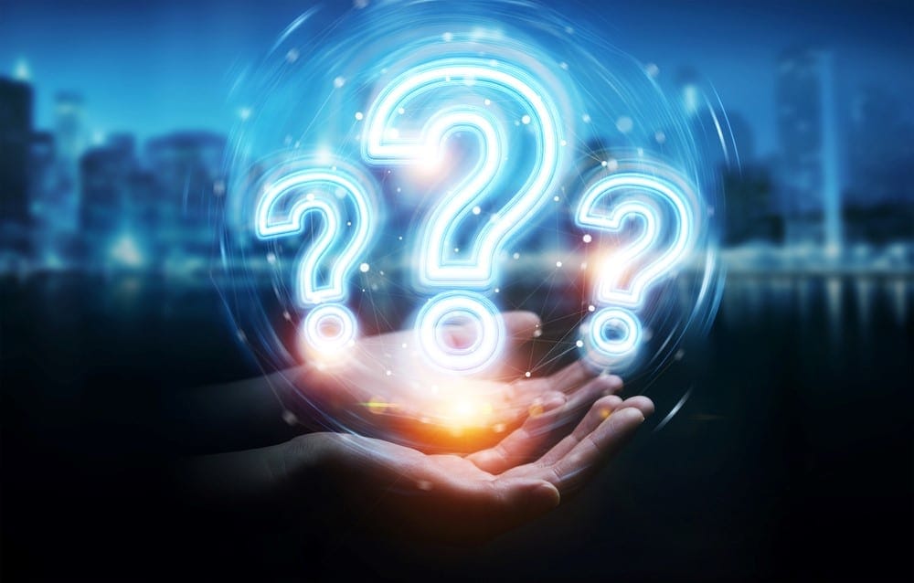 Hands holding glowing question marks in front of cityscape